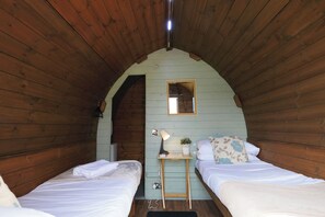 A cozy cabin with two wooden bunk beds, a small table with a lamp, and a window with a mirror.