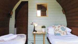 Une pièce confortable avec deux lits, une petite table avec une lampe, un miroir et une plante en pot.