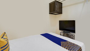 Une chambre d’hôtel avec un lit, un téléviseur fixé au mur et un luminaire suspendu.