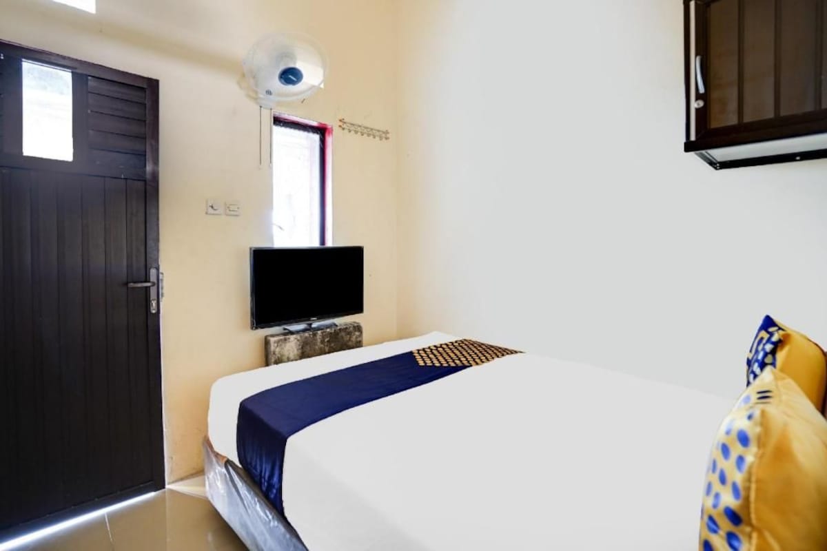 A hotel room with a bed, a television, a door, and a window.
