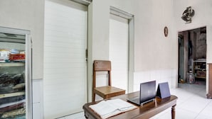 Une pièce avec une table en bois, deux ordinateurs portables, une chaise et une porte blanche fermée.