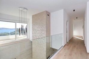 Un interior moderno con barandilla de vidrio, vistas al exterior y un pasillo que conduce a otra habitación.