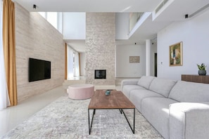 Una sala de estar moderna con una televisión de pantalla plana, chimenea, sofá y mesa de centro.