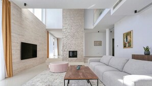 A modern living room with a flat-screen TV, a fireplace, a sofa, and a coffee table.