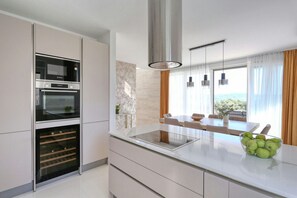 Eine moderne Küche mit integrierten Geräten, ein Essbereich mit Tisch und Stühlen sowie ein Ausblick durch große Fenster.