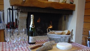 A table with a bottle of champagne, glasses, cheese, bread, and a cutting board. - Appartement Avec vue Panoramique sur la Vallée (Le Grand-Bornand)