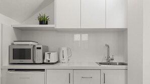 Une cuisine moderne avec des meubles blancs, un four à micro-ondes, un grille-pain, une machine à café et un lave-vaisselle.