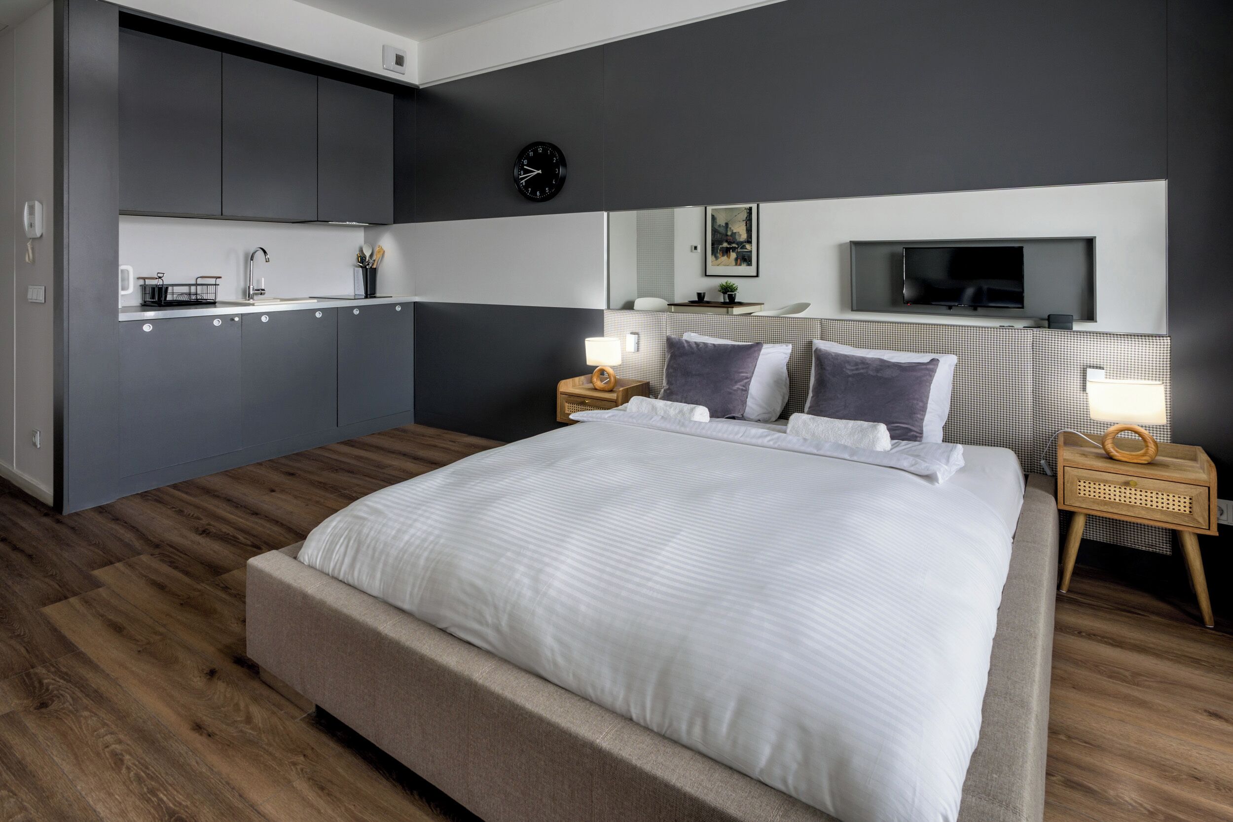 Une chambre moderne dotée d’un grand lit, de tables de chevet, d’un téléviseur et d’un coin cuisine intégré.