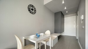 Ein moderner Essbereich mit einem weißen Tisch, Stühlen und einer Wanduhr.