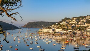 Un pueblo costero con numerosos barcos amarrados en un puerto, rodeado de edificios y colinas.