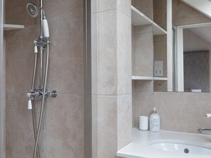 Un baño con ducha, lavamanos y espejo.