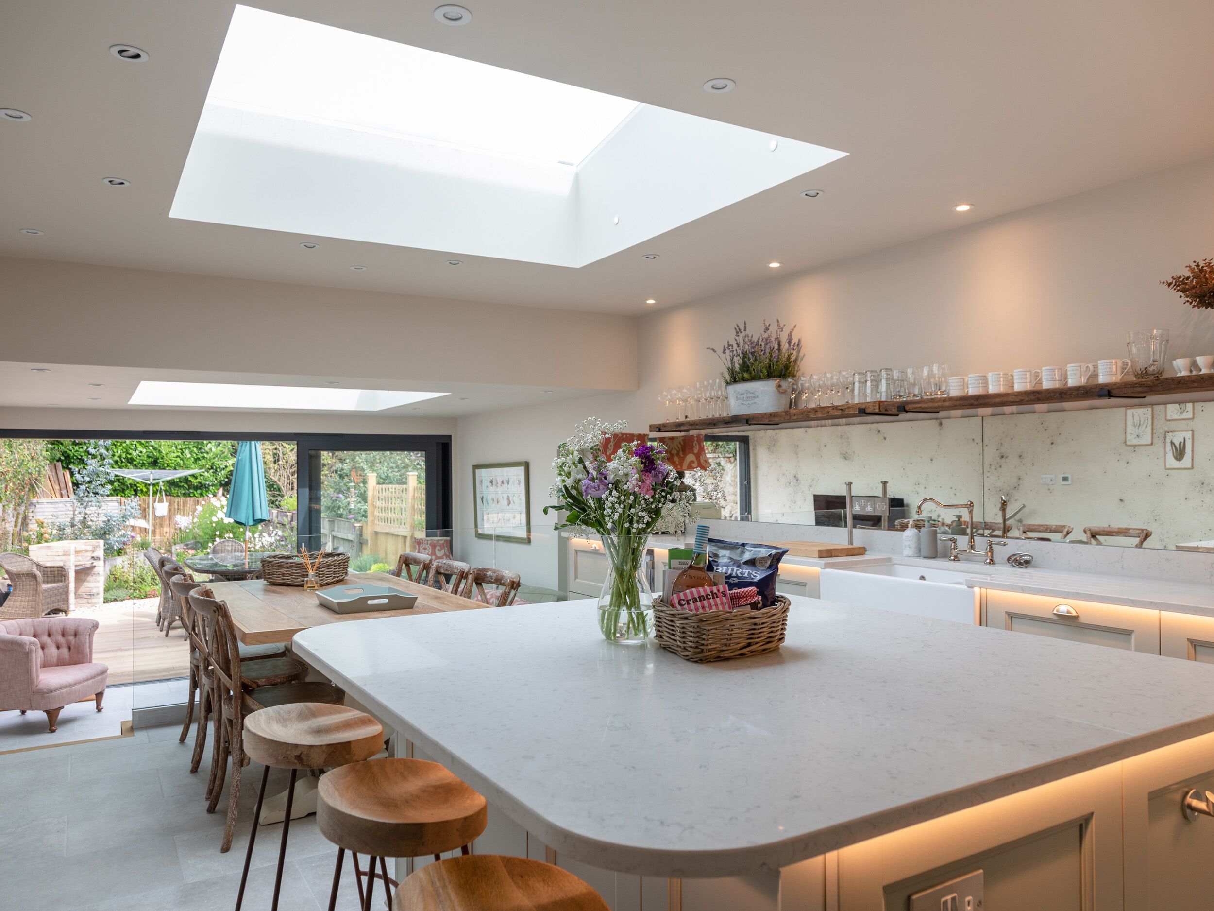 Een moderne keuken met een centraal eiland, barkrukken en een eethoek met een tafel en stoelen.