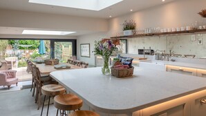 Una cocina moderna con una isla central, taburetes de bar y una zona de comedor con mesa y sillas.