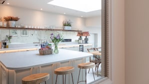 Una cocina moderna con una isla central, taburetes de bar y vistas al comedor.