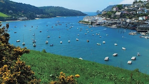 Un pueblo costero con numerosos barcos en el agua, un puerto deportivo y edificios en la ladera de la colina.