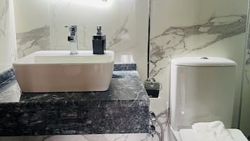 Une salle de bain avec un lavabo blanc, un plan de toilette en marbre noir et des toilettes blanches.
