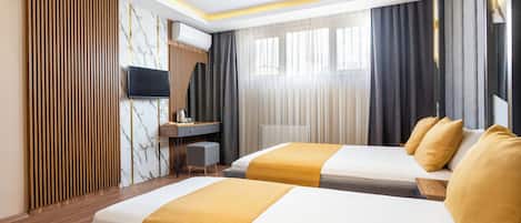 A hotel room with two beds, a desk, a TV, and a large window with curtains.