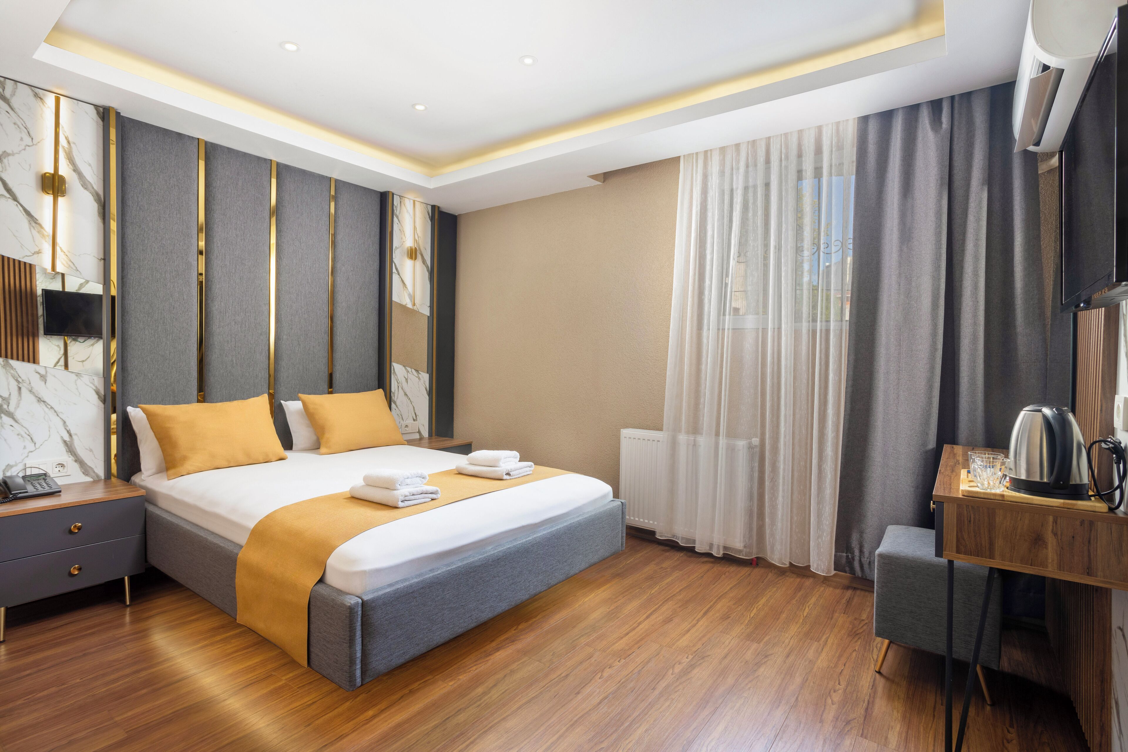 A modern hotel room with a large bed, bedside tables, a desk, and a television.
