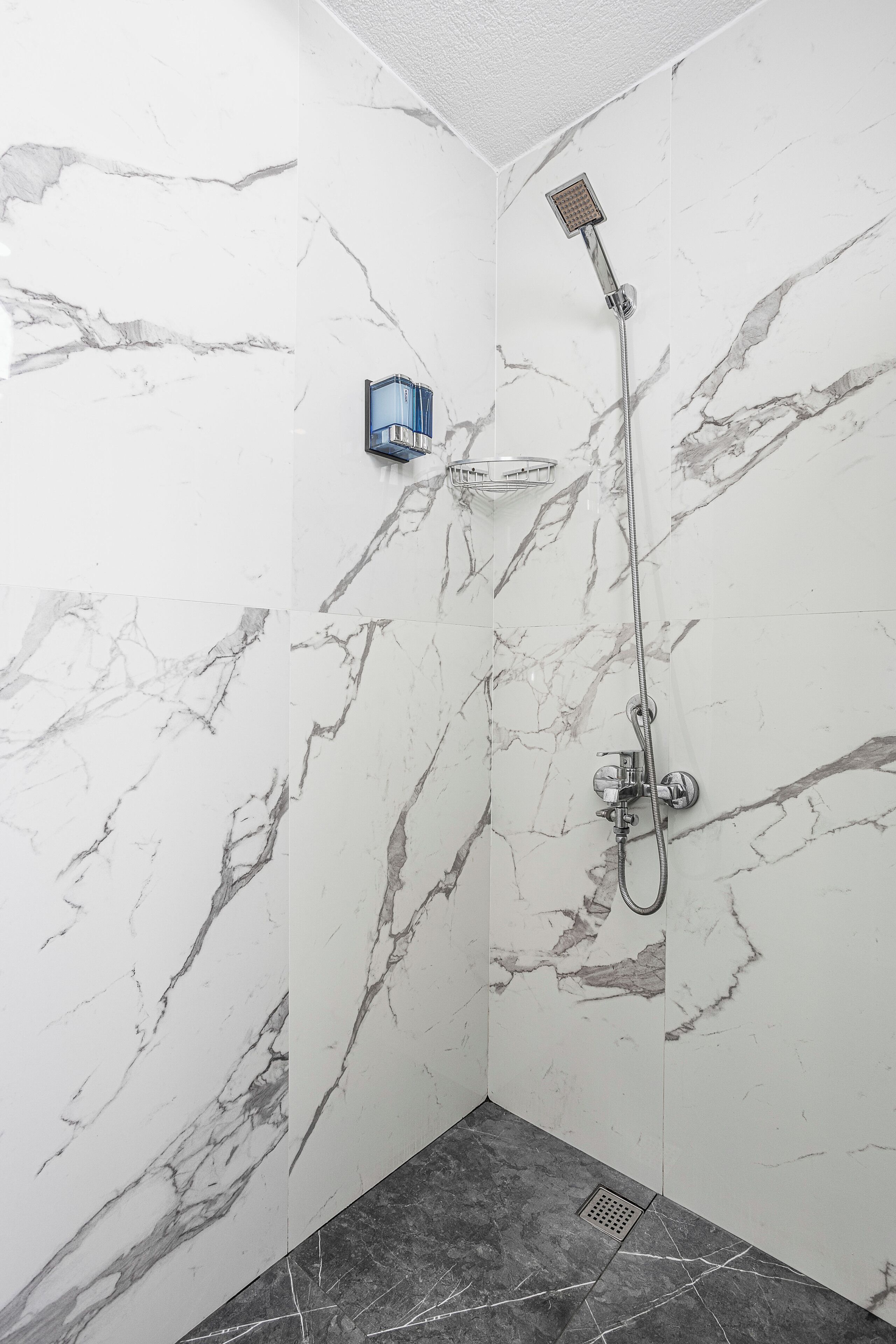 A bathroom with marble walls and a shower area.