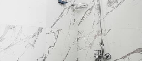 A bathroom with marble walls and a shower area.