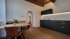 A modern kitchen with a wooden dining table, chairs, and a black cabinet with gold handles. - Fruemess Superior (Partschins)