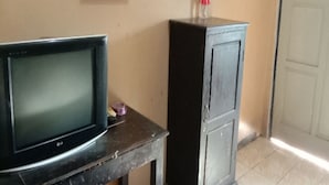 A television on a table, a cabinet, and a door in a room. - Hotel O Mutiara (Ponorogo)