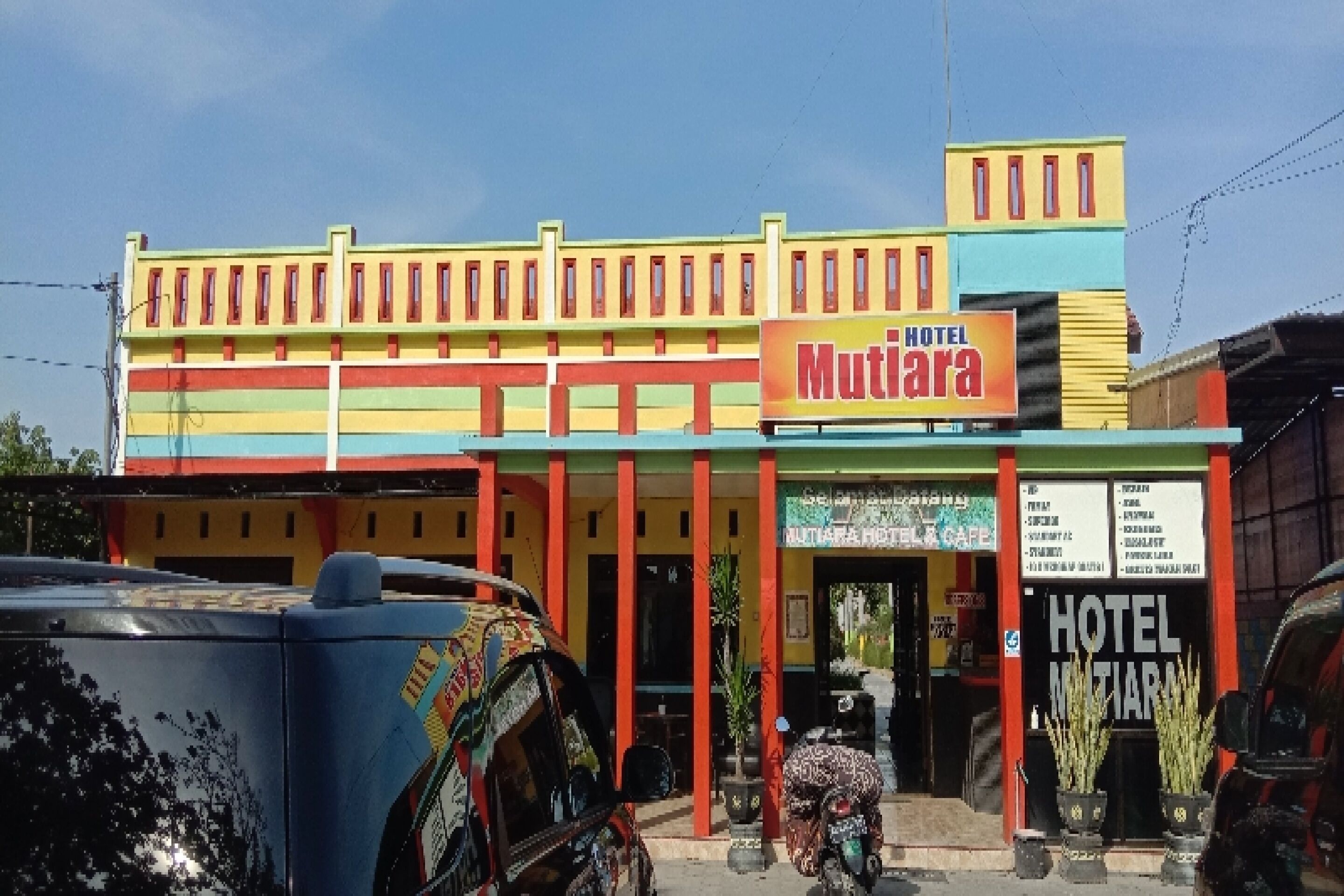 Un bâtiment aux couleurs vives, sur lequel on peut lire l’inscription « Hôtel Mutlara ».