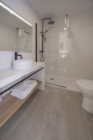 Une salle de bain moderne avec un lavabo blanc, un miroir et des toilettes.