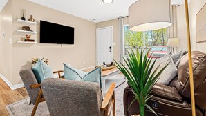 A living room with a flat-screen TV, a sofa, a coffee table, and a lamp.