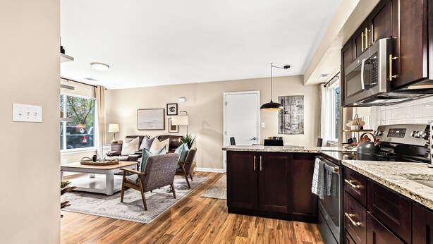 A modern kitchen with dark wood cabinets, a granite countertop, and stainless steel appliances.