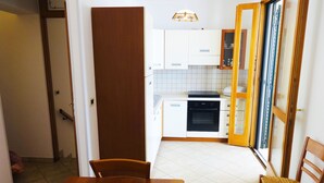 A compact kitchen with white cabinets, a black oven, and a wooden dining table with chairs.