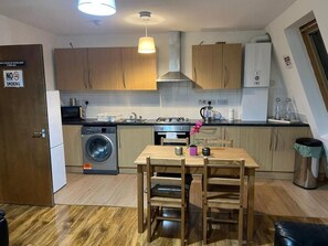 Compact kitchen with modern amenities, featuring a gas stove, washing machine, and dining area.