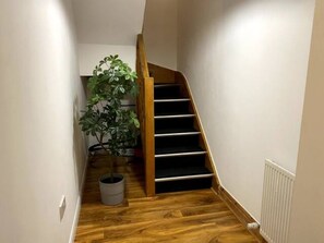 Staircase leads to a cozy space with a potted plant and radiator.