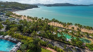 A resort with a swimming pool, beach, and palm trees. - Whitsunday Apartment West 1302 (Hamilton Island)