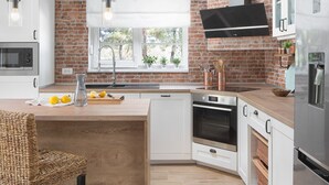 A modern kitchen with exposed brick walls, wooden beams, and stainless steel appliances. - Allegra Istriana in Fa ana (Fazana)