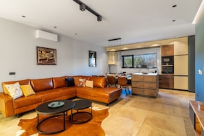 Uma sala de estar moderna com sofá seccional, área de refeições e cozinha com uma janela grande.