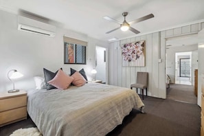 A bedroom with a bed, nightstands, a ceiling fan, and a large mirror.