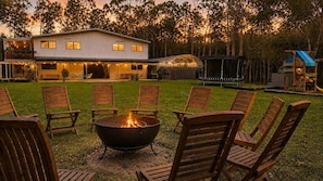 A backyard with a fire pit, outdoor seating, and a house in the background.