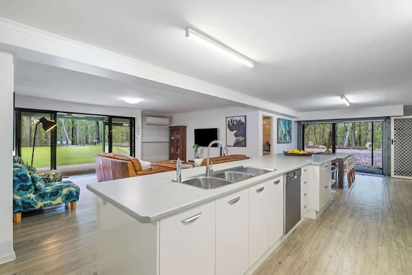 A modern kitchen with a large island, built-in appliances, and a view of the outdoors.