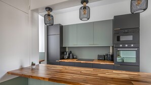 Una cocina moderna con encimera de madera, electrodomésticos integrados e iluminación colgante.