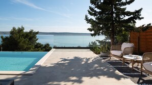 A poolside area with a view of a lake, outdoor furniture, and a wooden structure. - Soho in Starigrad With 6 Bedrooms and 6 Bathrooms (Starigrad)