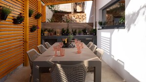 A dining area with a wooden table and chairs, surrounded by potted plants and a stone wall. - Soho in Starigrad With 6 Bedrooms and 6 Bathrooms (Starigrad)