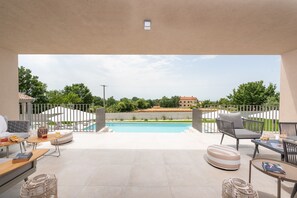 Un amplio espacio exterior con piscina, zonas de estar y vistas del paisaje circundante.