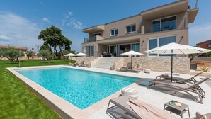 A modern two-story house with a swimming pool, outdoor seating, and a stone wall. - Levlante in Kanfanar (Kanfanar)
