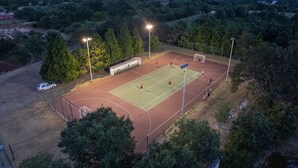 An outdoor tennis court surrounded by trees, with floodlights and a goal post. - Levlante in Kanfanar (Kanfanar)