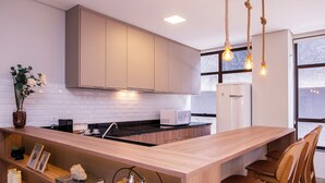 Una cocina moderna con armarios de madera, una isla integrada con asientos y vistas amplias a través de grandes ventanas.