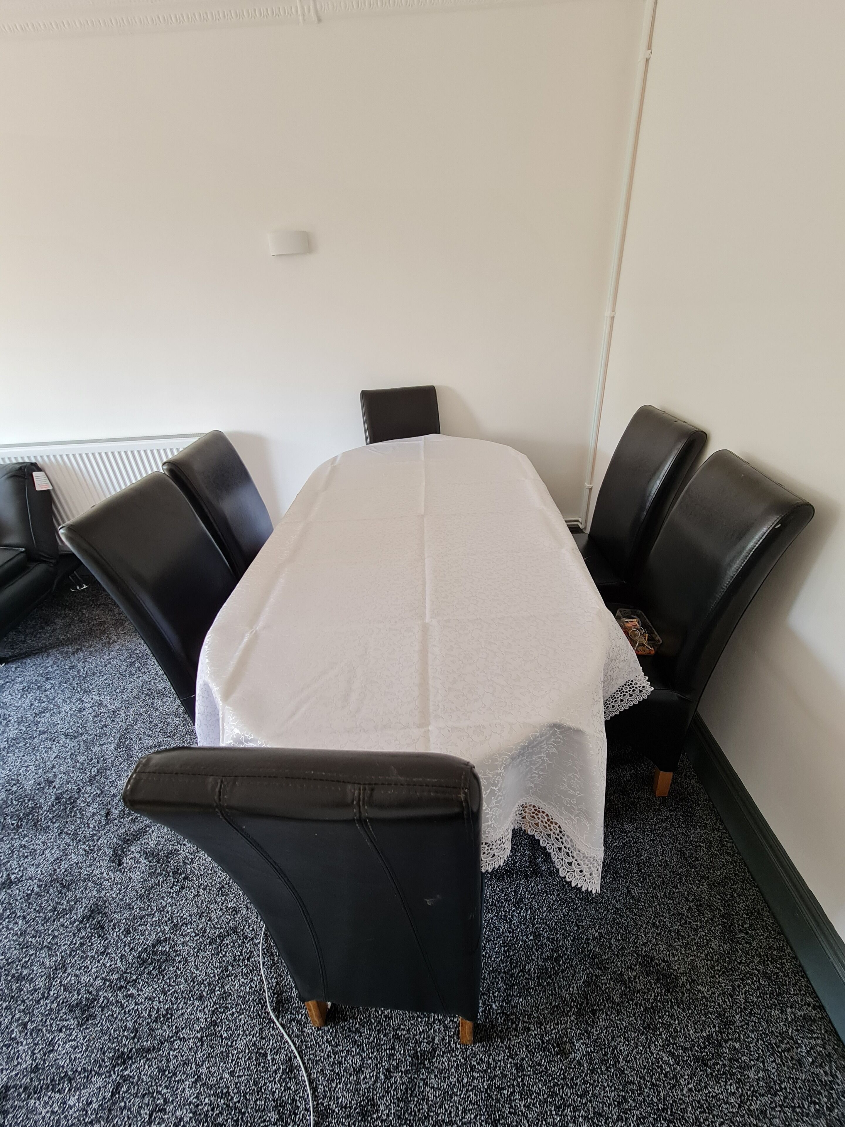 A conference room with a white table, black chairs, and a carpeted floor.