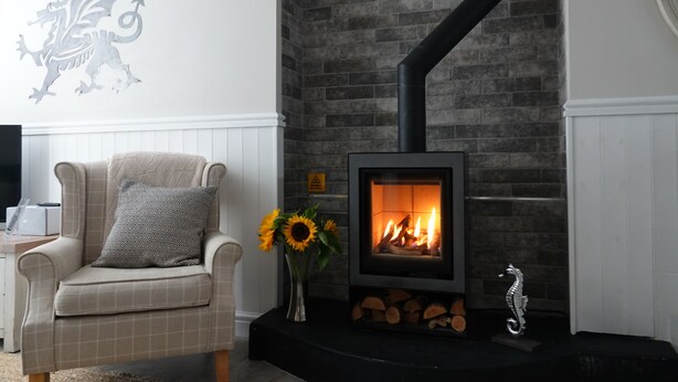 A cozy living room with a fireplace, a comfortable armchair, and a decorative seahorse. - 3 Bedroom Cottage in the heart of Conwy | Parking | Sleeps 4 (Conwy)
