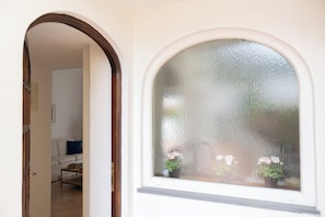 Een rondboogvenster met geëtste glas, een doorgang naar een woonkamer met een witte bank en een salontafel.