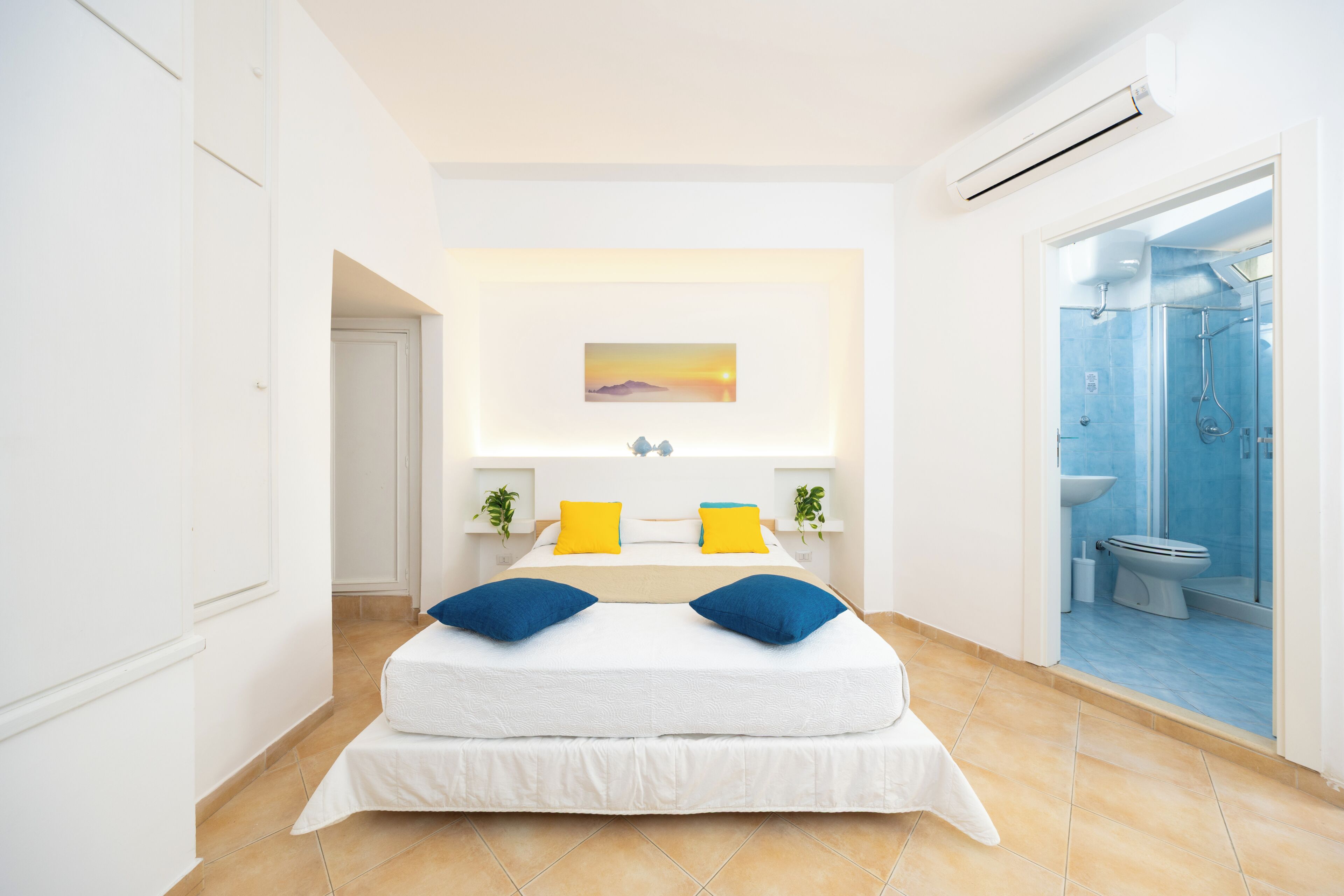 A modern bedroom with a bed, a painting, and a shower area.